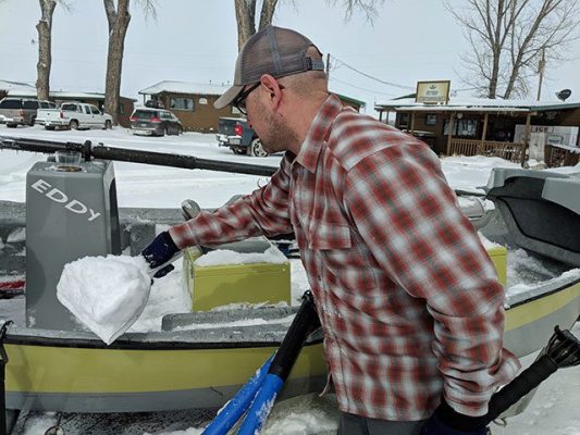 Forrest Jay shovels snow out of drift boat on the Bighorn River